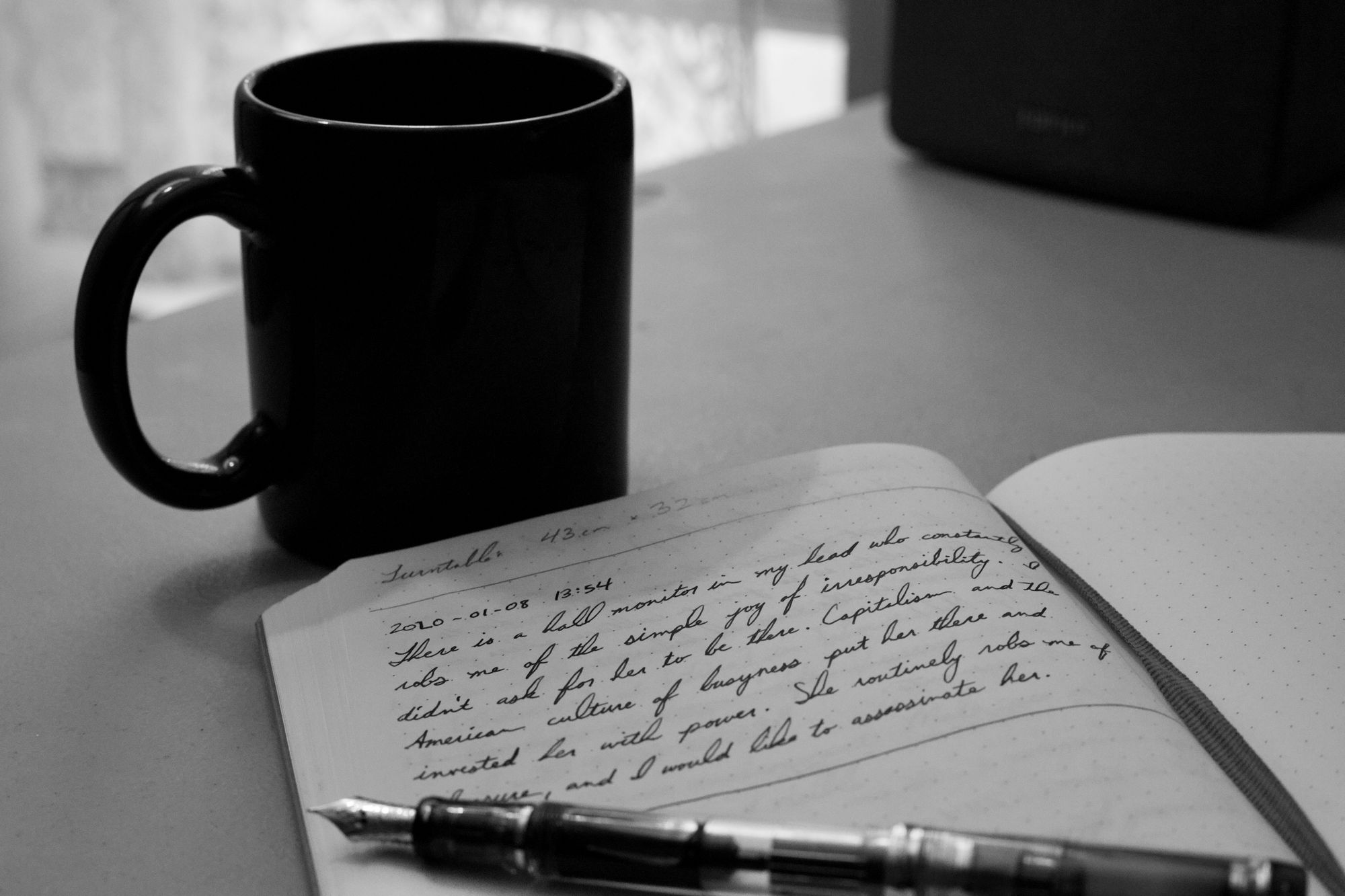 Notebook with cursive handwriting, a fountain pen, and a coffee mug