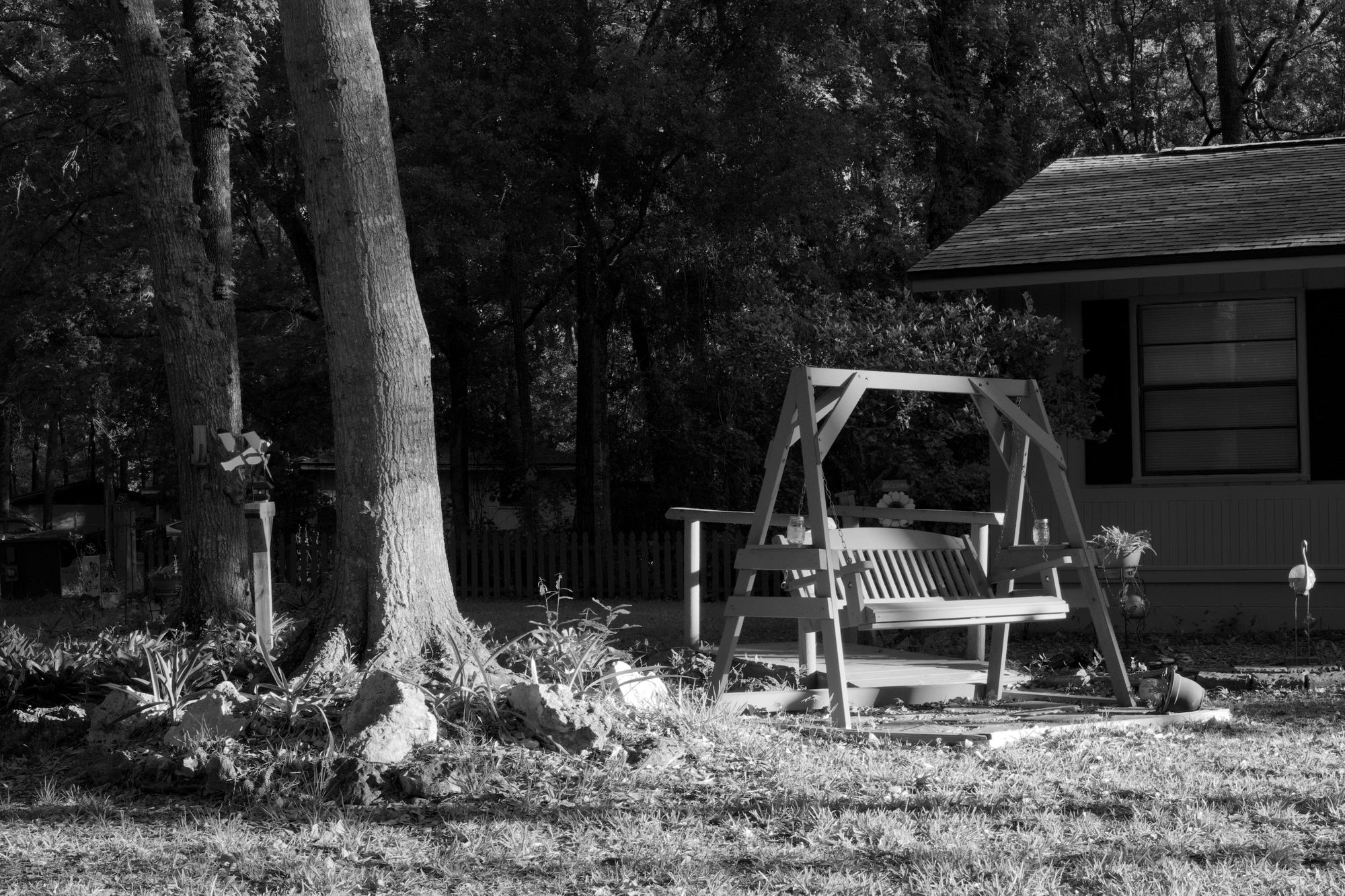 Swinging bench in a pool of morning light in a front garden.